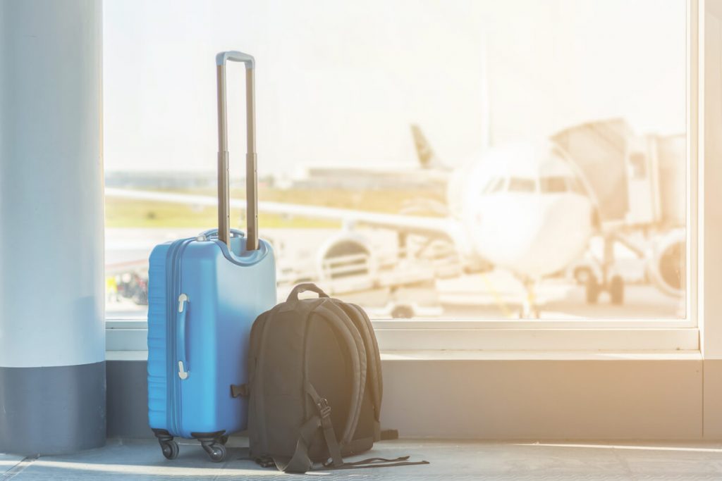 Imagem de mala e mochila de viagem no aeroporto de pessoas que viajam e não deixam milhas expirar.