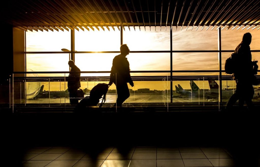 imagem de aeroporto no por do sol com os passageiros trafegando pelo saguão