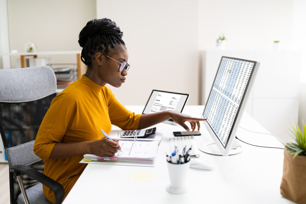 Mulher africana avaliando em seu computador sobre declaração de milhas no seu imposto de renda.