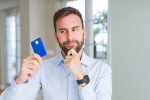 Homem confuso segurando o cartão de débito.