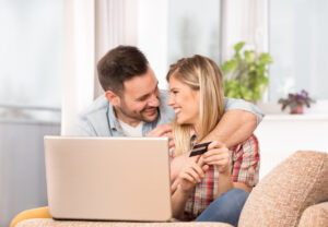 Jovem casal feliz fazendo compras online para acumular pontos no cartão de crédito, depois converter para milhas em o seu programa de fidelidade e vendê-las.