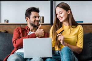 Jovem casal fazendo compras online no seu notebook com seu cartão de crédito Santander para acumular pontos Esfera.