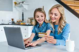 Feliz mãe e filha comprando online com laptop e cartão de crédito em casa para acumular pontos em cartões de crédito.