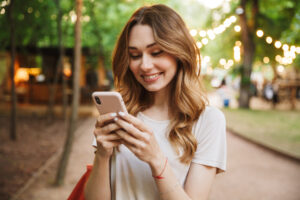 Jovem sorridente segurando um celular, olhando as tendências sobre compra e venda de milhas em 2022.
